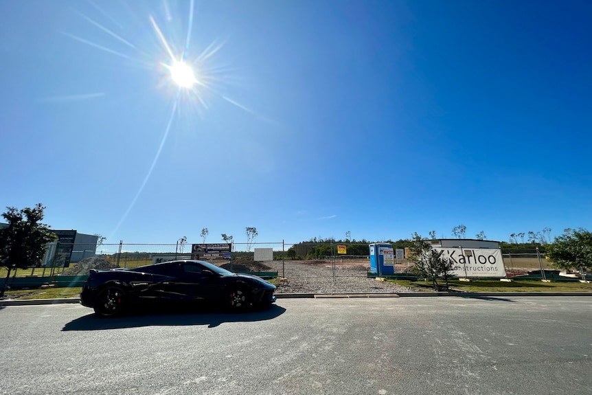 A black corvette car parked outside a construction site