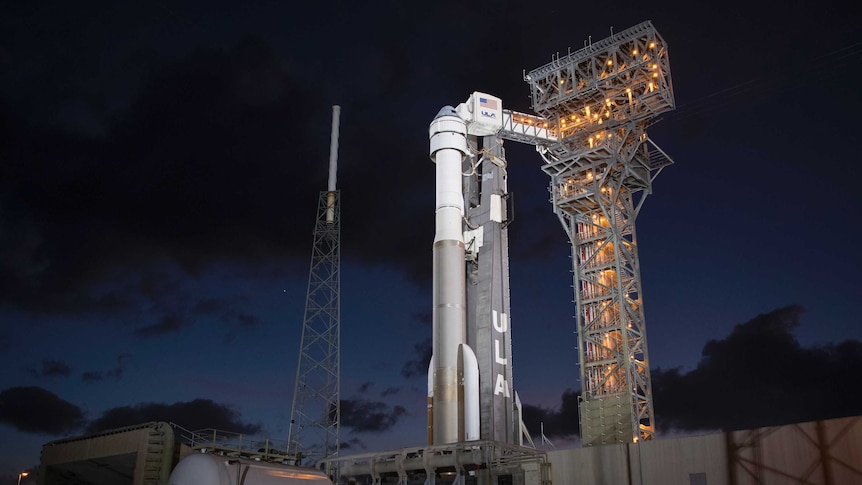 Boeing's CST-100 Starliner spacecraft is seen illuminated by spotlights on the launch pad at Space Launch Complex 41 at night.