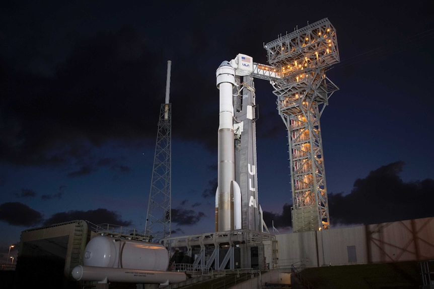 Boeing's CST-100 Starliner spacecraft is seen illuminated by spotlights on the launch pad at Space Launch Complex 41 at night.