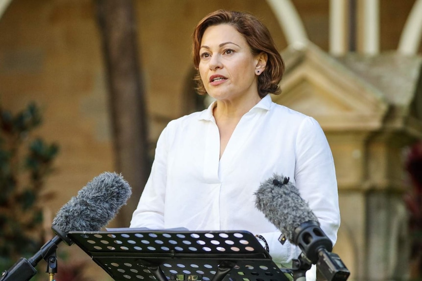 Jackie Trad stands at a lectern with two microphones.