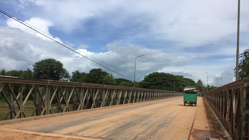 Photo of bridge with car driving across it in provincial Cambodia