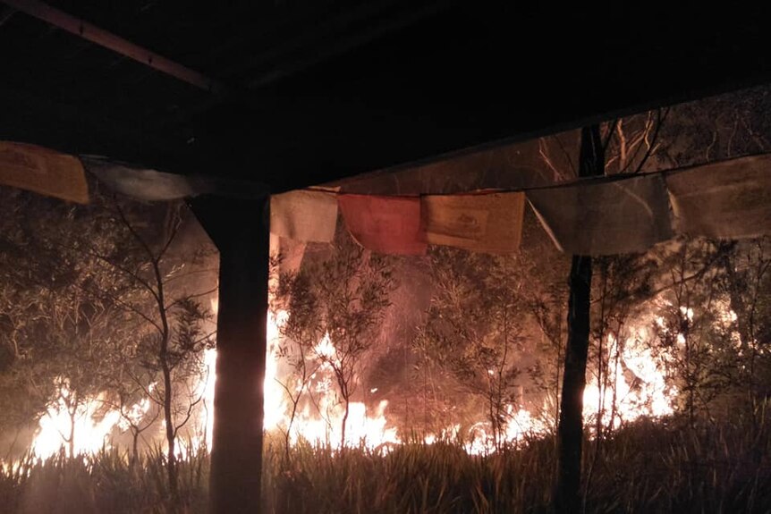 A bushfire burning close to a house at night