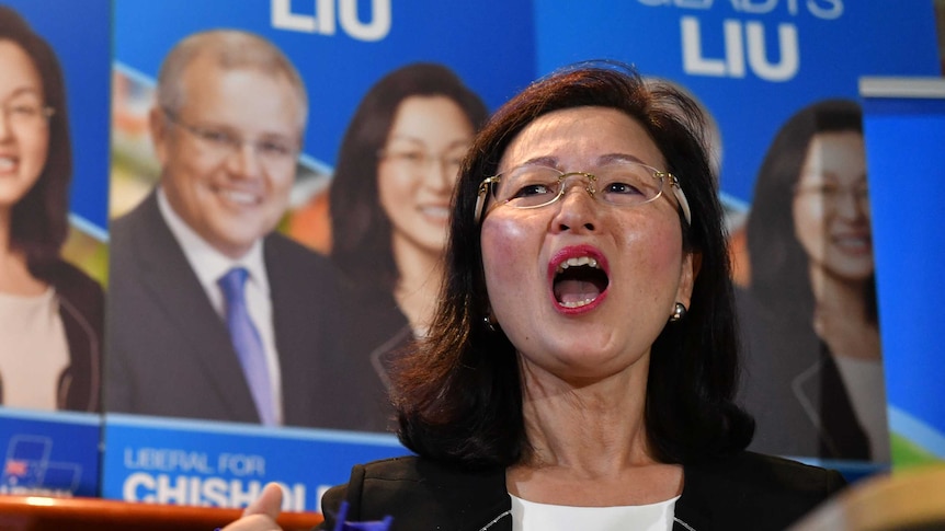 Liberal candidate for Chisholm Gladys Liu speaks with campaign posters in the background.