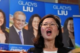 Liberal candidate for Chisholm Gladys Liu speaks with campaign posters in the background.