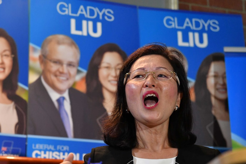 Liberal candidate for Chisholm Gladys Liu speaks with campaign posters in the background.