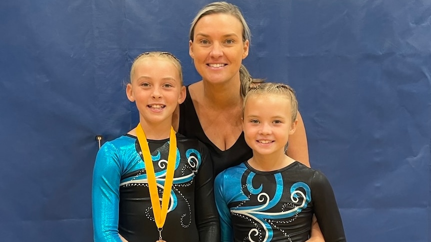 Two kids in gymnastics outfits pictured with their mum