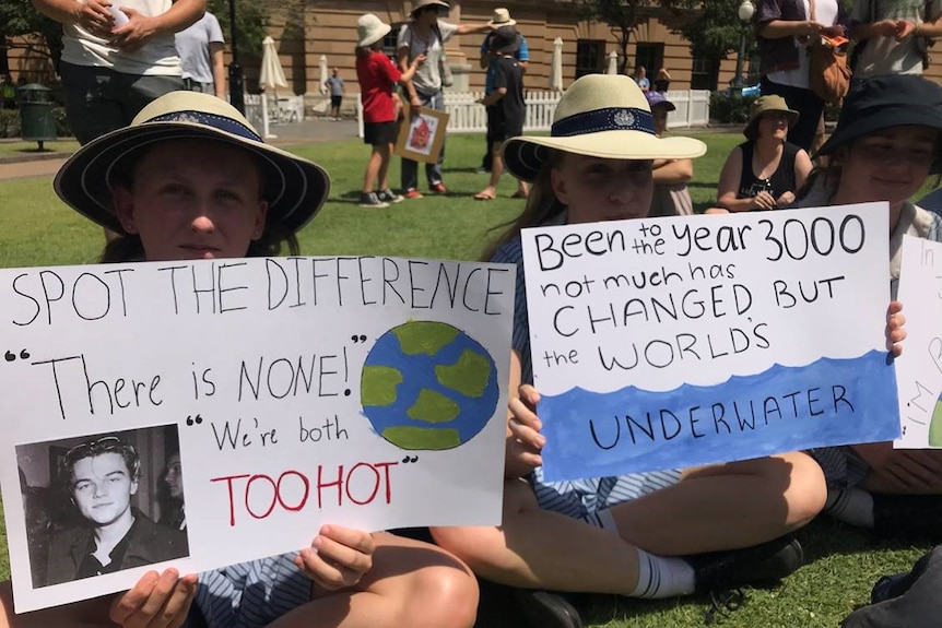 Two school students with hats on carrying signs