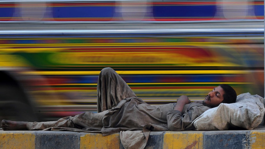 A Pakistani homeless man rests on a median on a road in Karachi