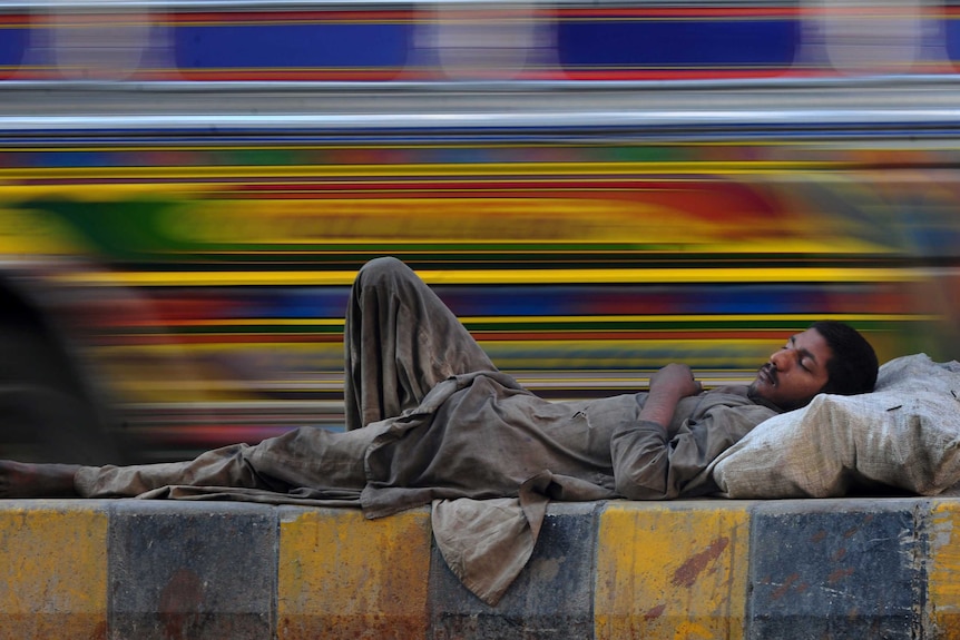 A Pakistani homeless man rests on a median on a road in Karachi