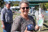 Bowler Wendy Coleman at Canungra Bowls Club holding a bowl and hand sanitiser.