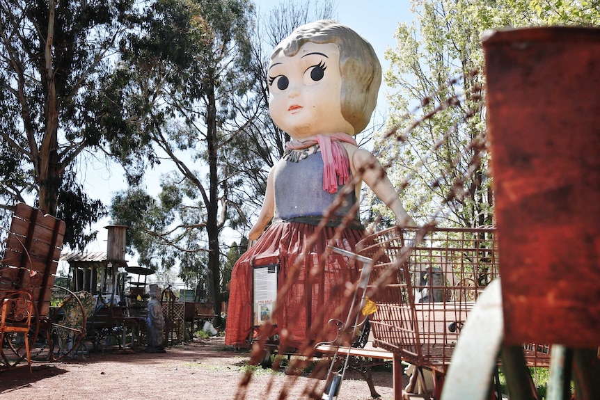 Giant kewpie doll with barbed wire in foreground