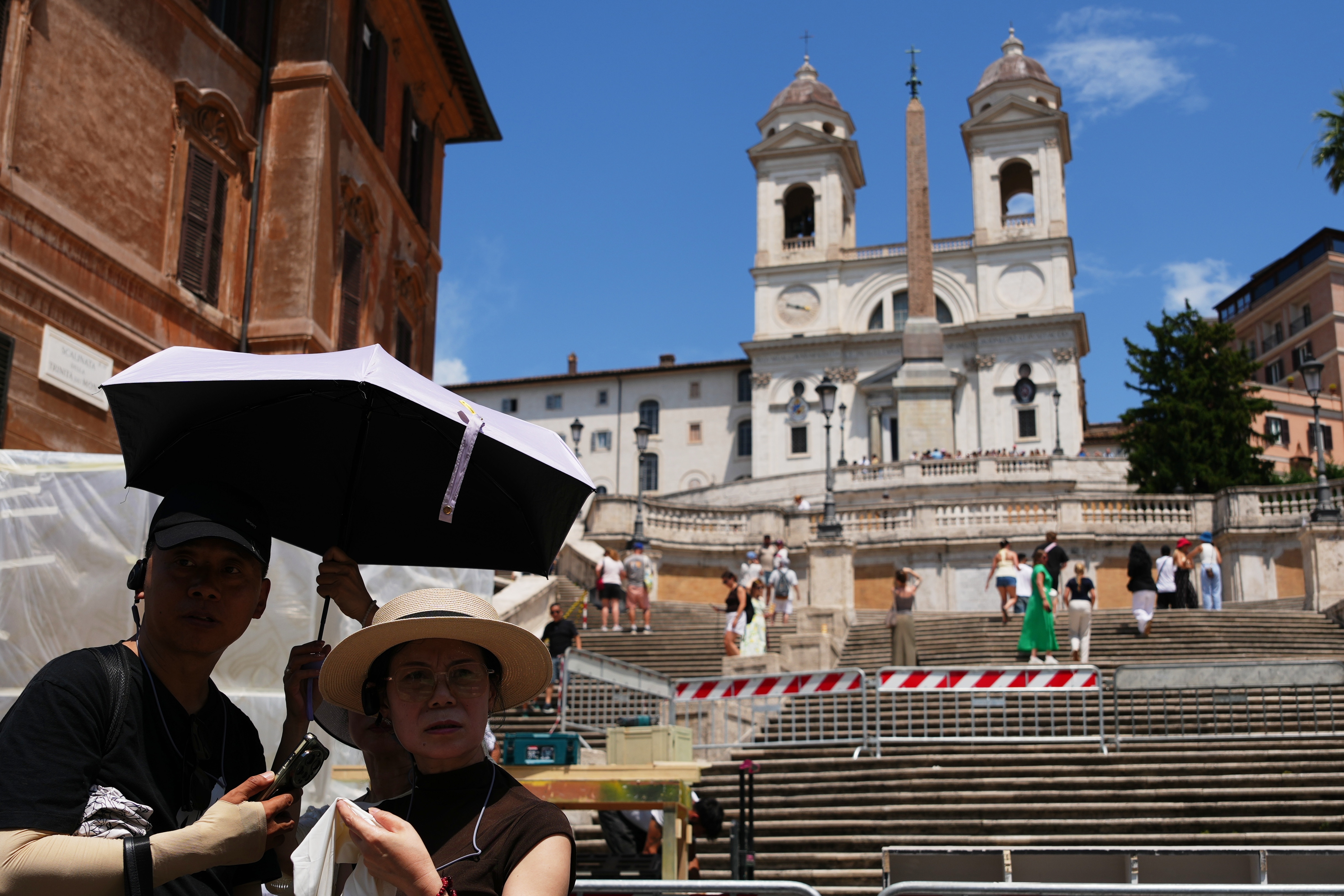 Tourists use umbrellas to shelter from the sun as they visit the Spanish steps in Rome.