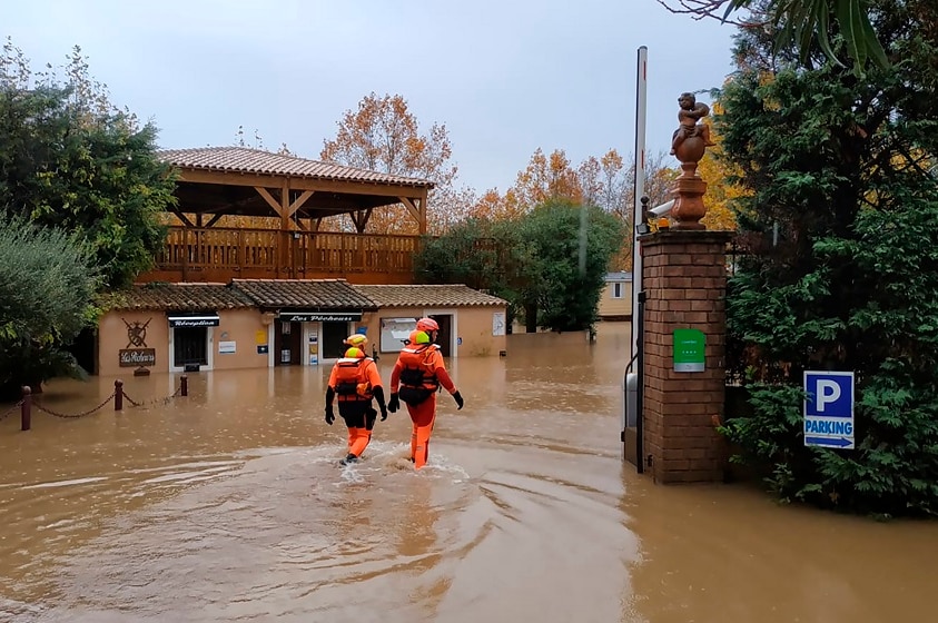 rescue workers wading through floodwaters in France.