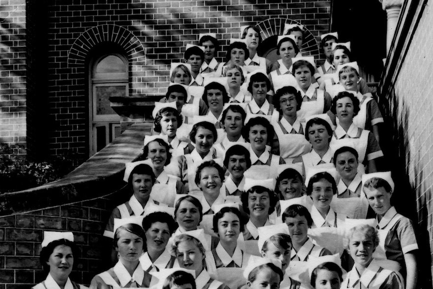 A black and white archive picture of a group of nursing students posing for a photo standing on stairs in 1963.