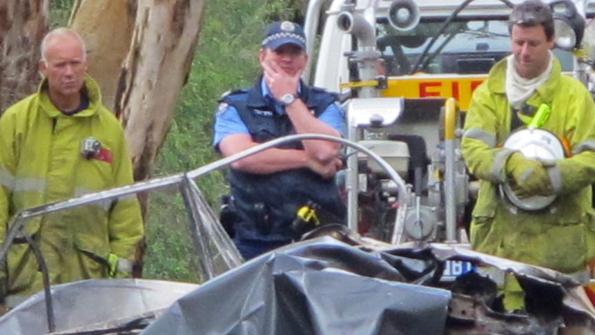 Police and firefighters look at burnt car at scene of a fatal crash at Torbay, near Albany