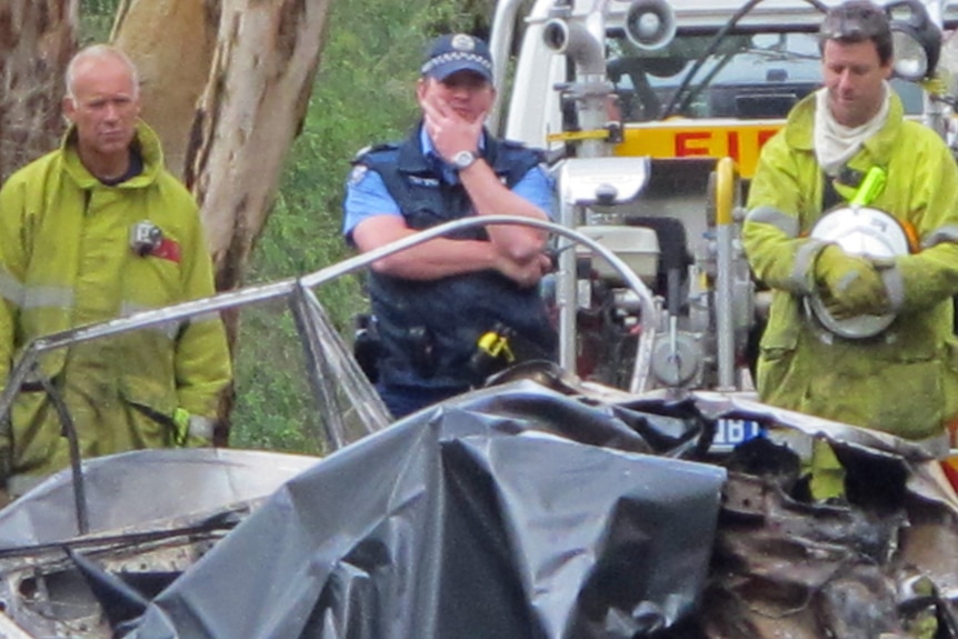 Police and firefighters look at burnt car at scene of a fatal crash at Torbay, near Albany