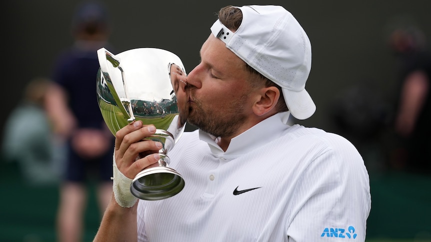 Dylan Alcott kisses the Wimbledon trophy