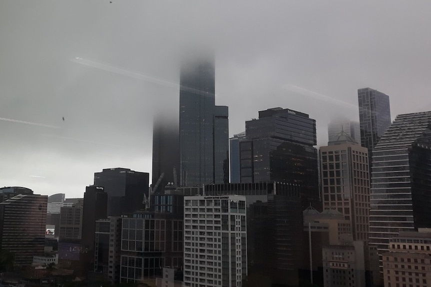 The view of a stormy Melbourne skyline from a skyrise window.
