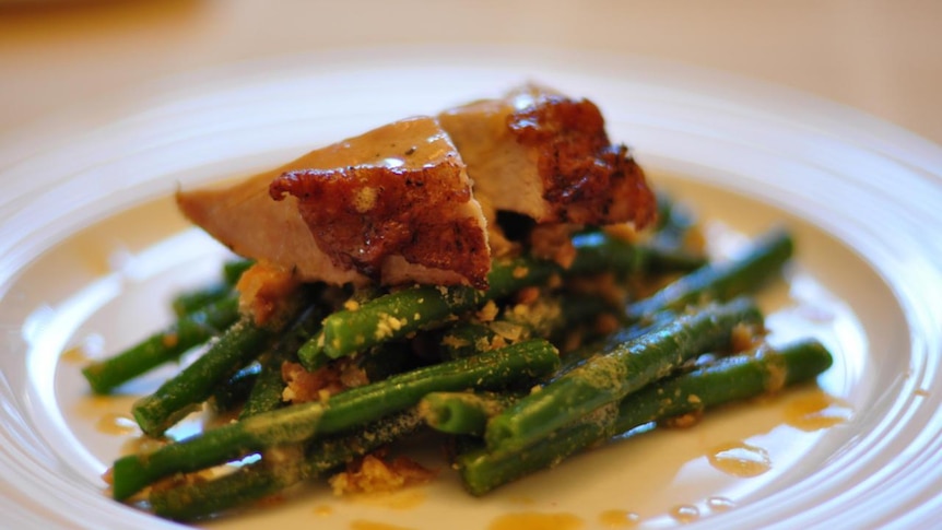 Slices of pheasant meat on top of a plate full of green beans.