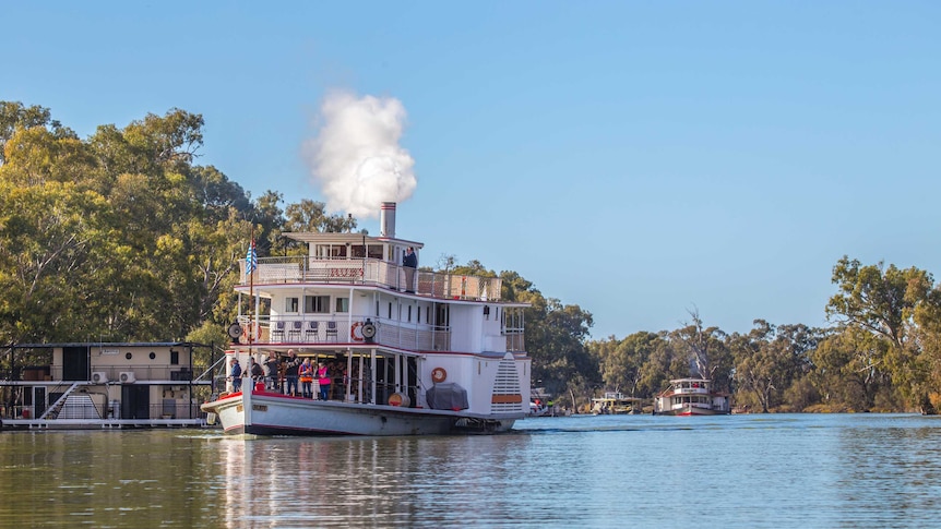 paddle steamer driving down river, with a plume of smoke steaming from above