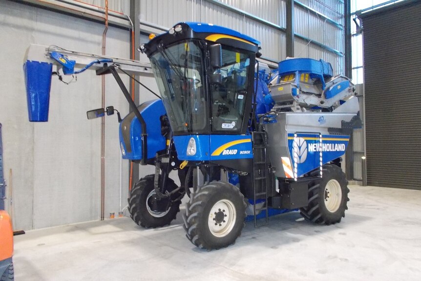 A big blue grape harvester sits quietly in a new winery at Penna