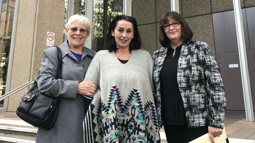 Three women look at the camera.