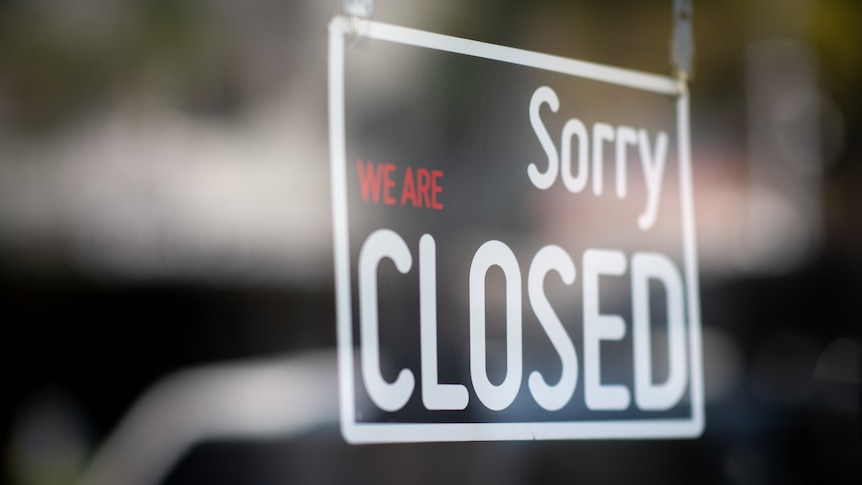 A "sorry we're closed" sign in the window of a shopfront.