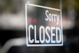 A "sorry we're closed" sign in the window of a shopfront.