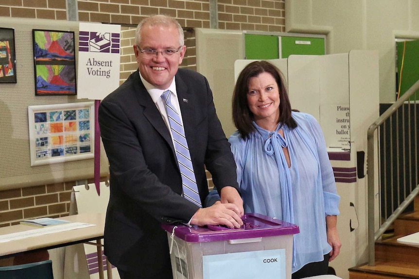 Prime Minister Scott Morrison and his wife Jenny smile for the cameras as they put their ballot paper in a box