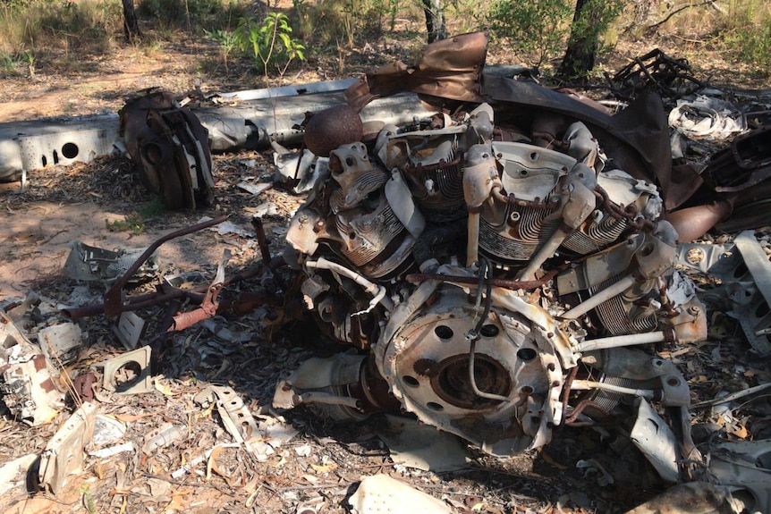 Crushed metal and machinery from the wreckage of a plane lying in scrub land.