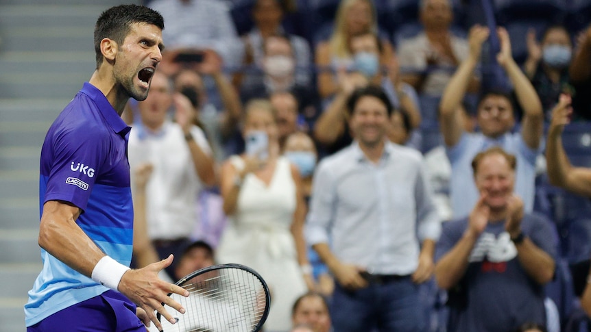 A male tennis player screams out as he celebrates winning a point.