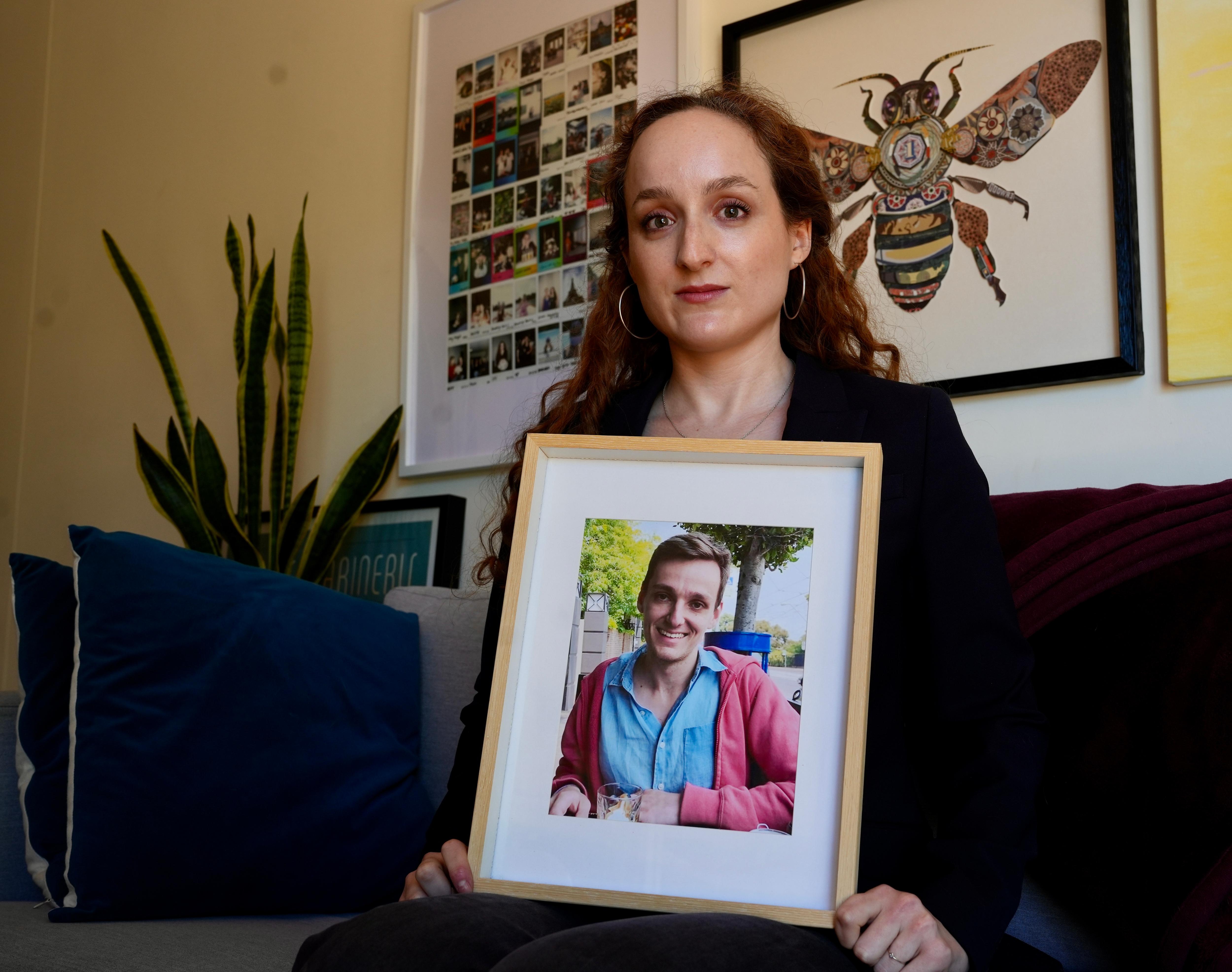 Uma mulher segurando uma fotografia emoldurada de um homem.
