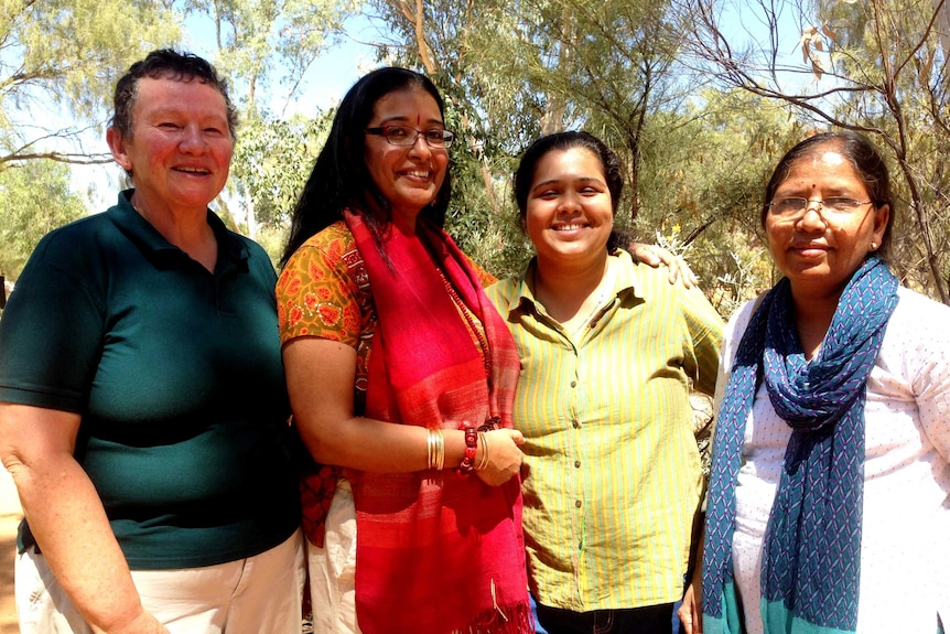 Four academics standing next to each other. Bushland is around them.