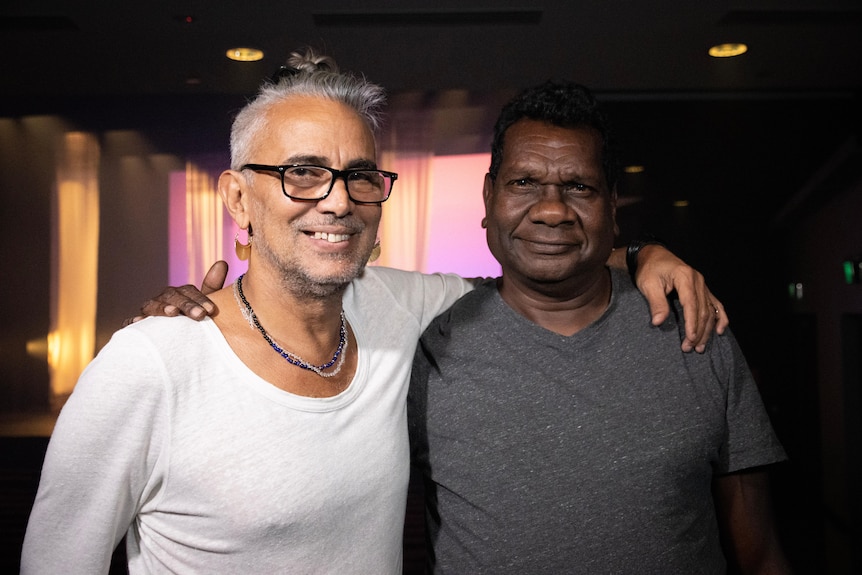 A portrait of two men in front of a stage.