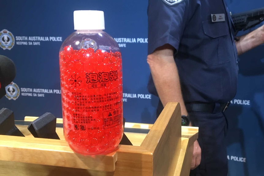 A clear bottle containing pink shiny balls
