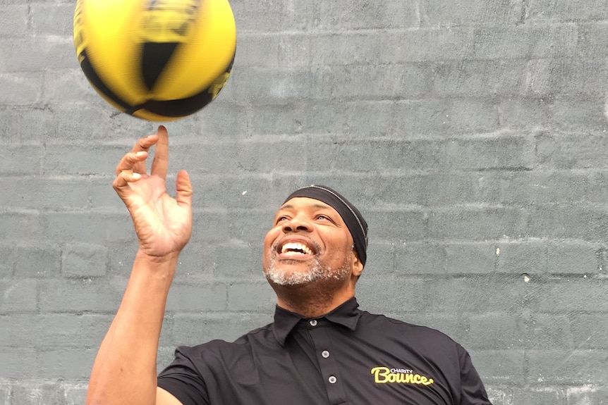 Tracy Williams smiles and spins a basketball on his finger.
