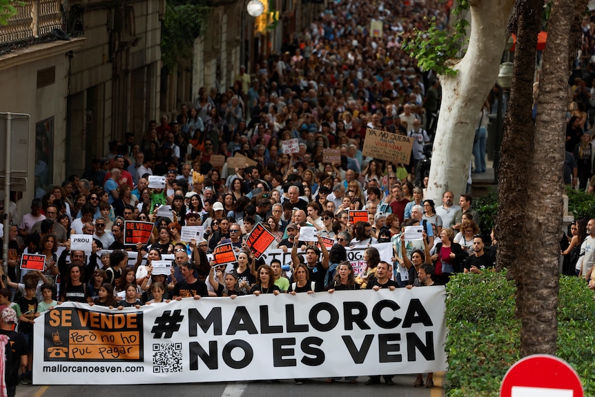 People hold a banner that reads "Mallorca is not for sale", as they take part in a protest against mass tourism.