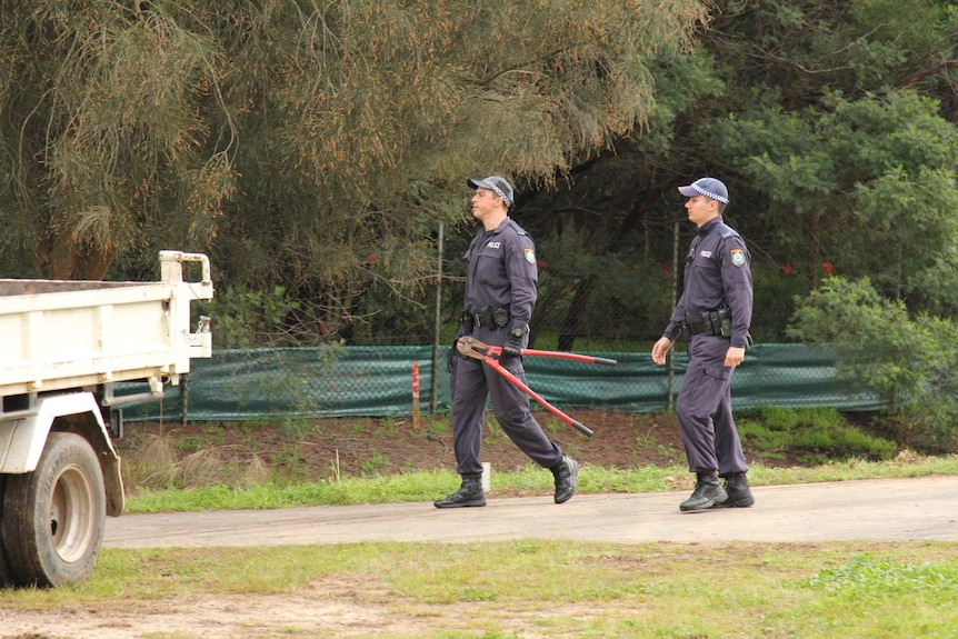 Two police walking with bolt cutters.