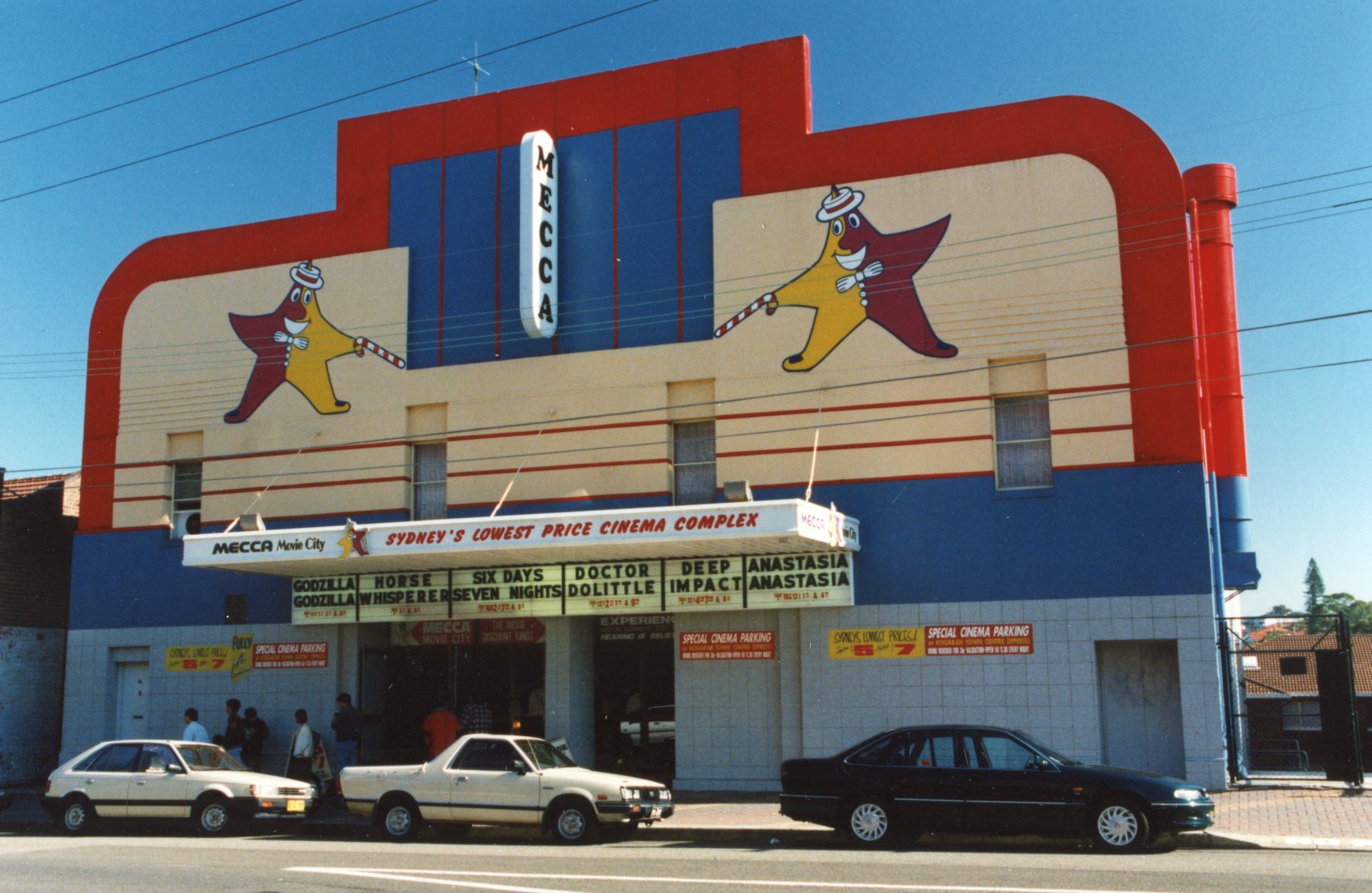 Una vista externa del Cinema de la Meca en Kogarah a fines de la década de 1990, con algunos autos fuera del frente.