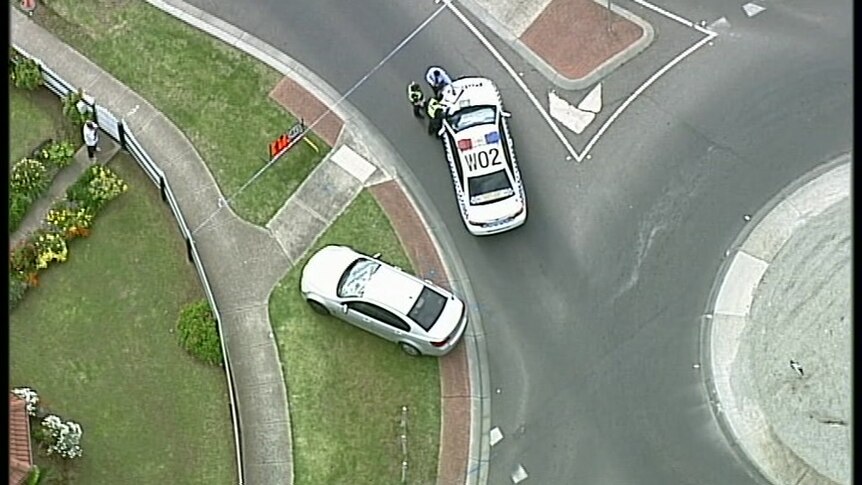 An aerial view of a police car near a roundabout on a street, parked near another car.