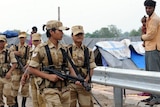 Soldiers march past workers' tents