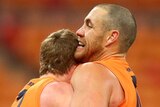 Two GWS Giants AFL players embrace as they celebrate beating Collingwood.