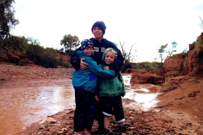 A woman and two children in a creek bed.