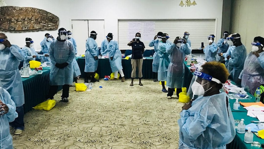 Dozens of PNG healthcare workers stand in scrubs, face shields and masks