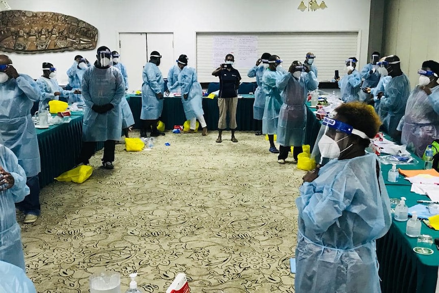 Dozens of PNG healthcare workers stand in scrubs, face shields and masks