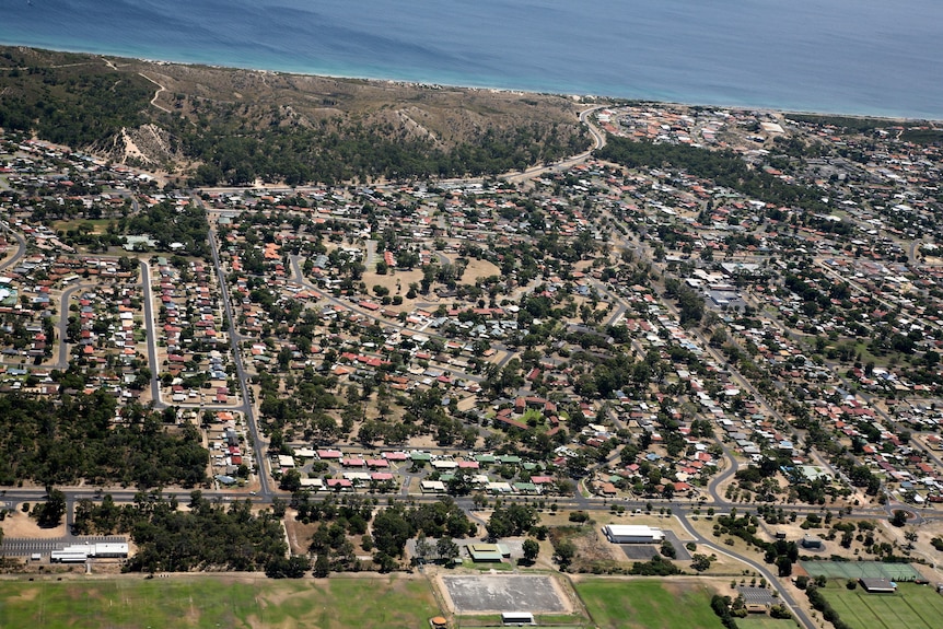 An aerial shot of a suburb showing long winding streets and dead ends with a beach and sports centre on either side.