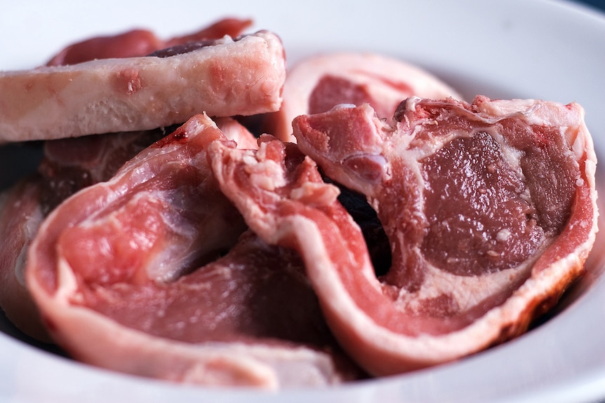 A close up photo of some raw lamb chops