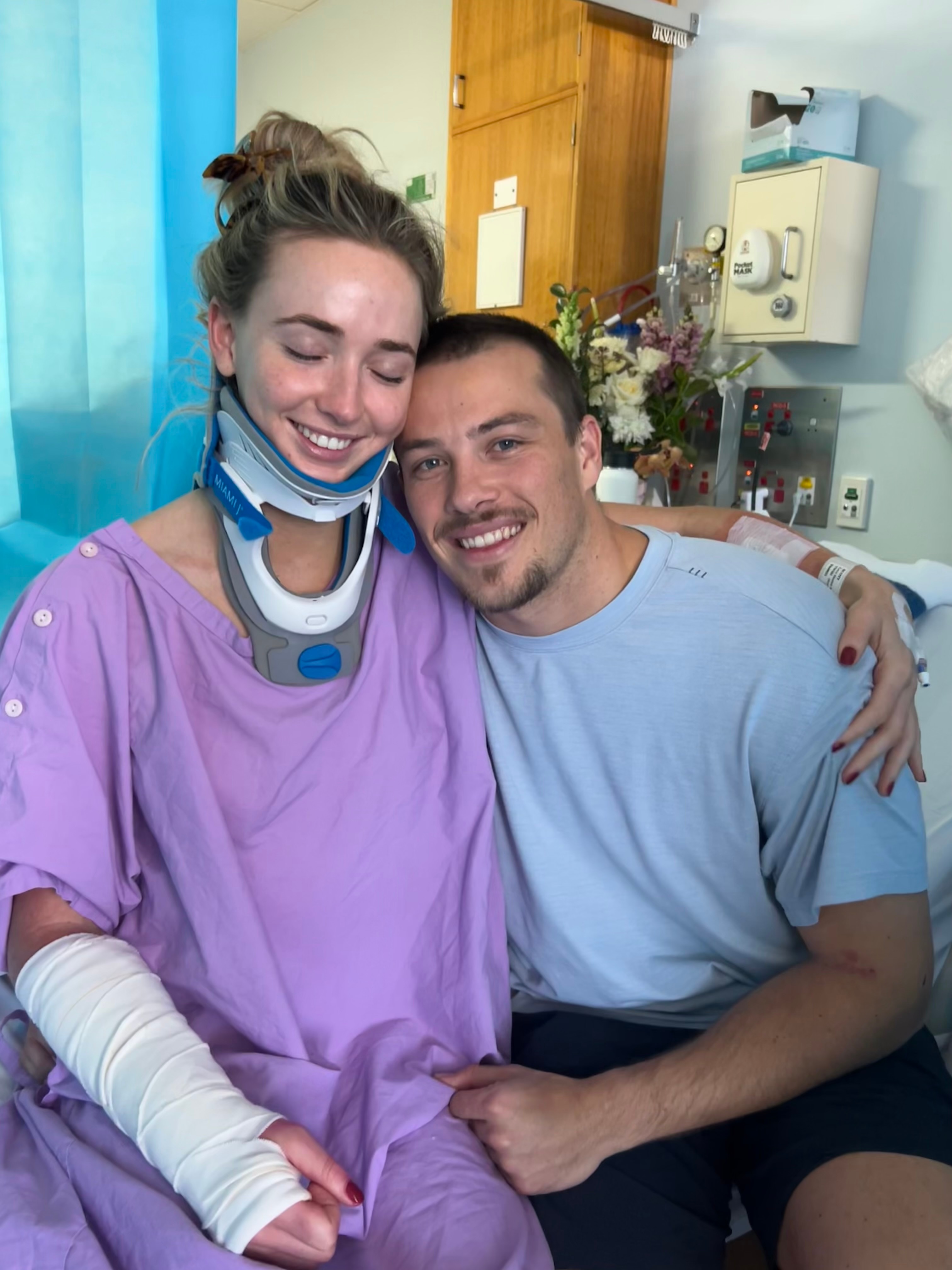 Lucy Scott wearing a neck brace in hospital with her partner Jethro Tessan.