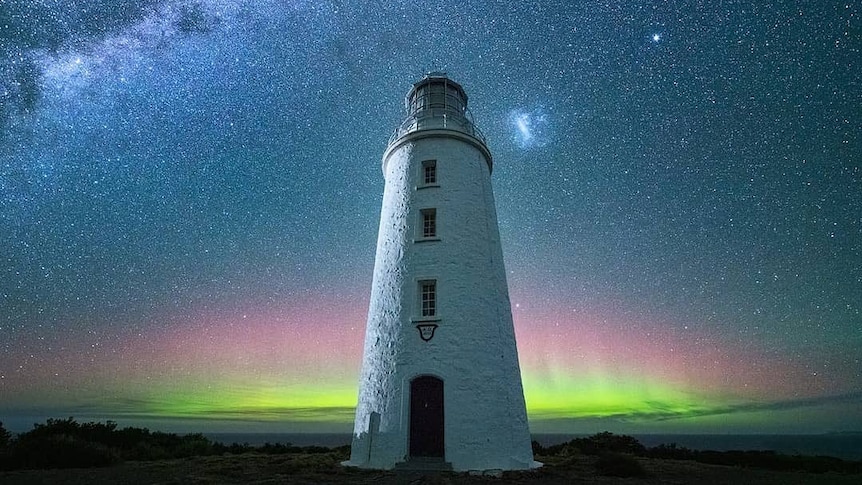 A lighthouse in front of a night sky and the green lights of an Aurora Australia