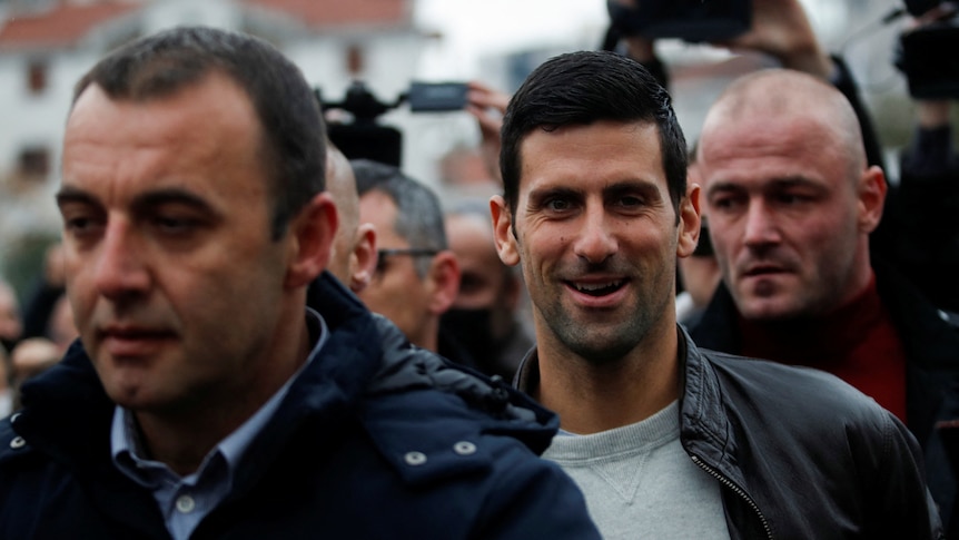 Novak Djokovic looks at the camera while walking among a crowd of people in Montenegro